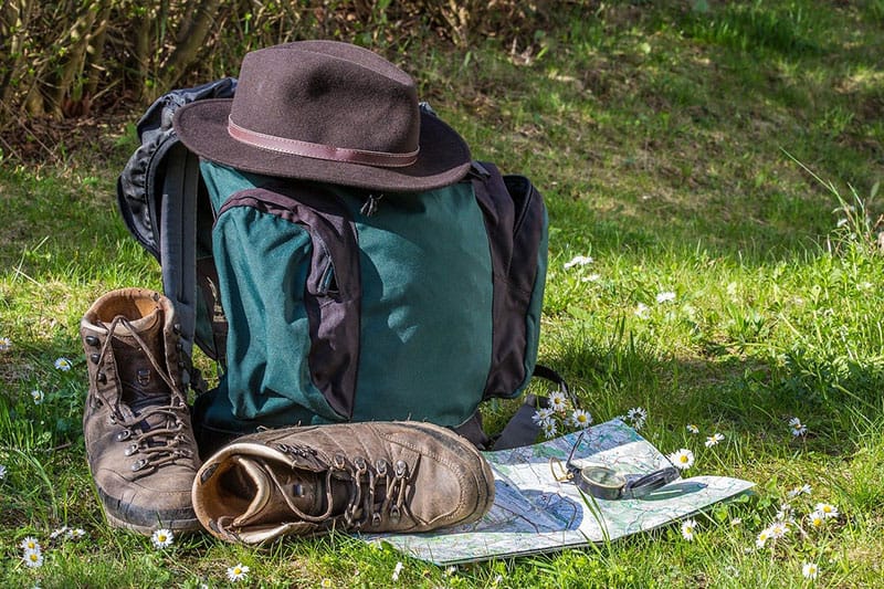 photo of hiking boots, a backpack, map, and compass